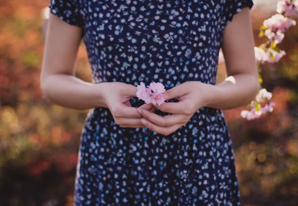 Mãos segurando pequenas flores com delicadeza